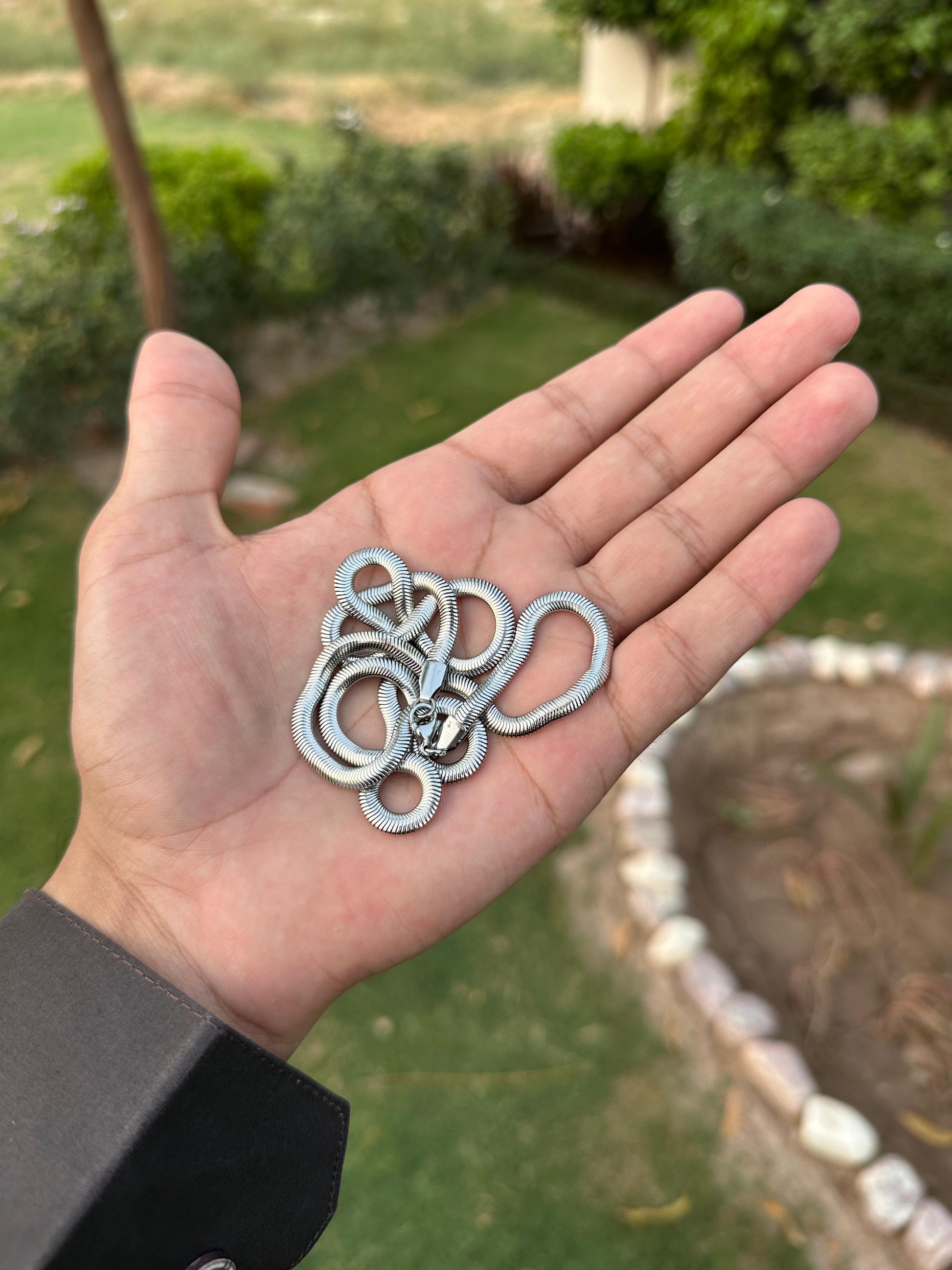 Hand holding  silver Chain with a garden background